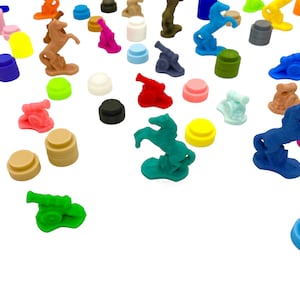 Puede incluir: Una colección de juguetes de plástico en miniatura de colores, incluyendo caballos, cañones y otras figuras. Los juguetes están dispuestos sobre una superficie blanca.