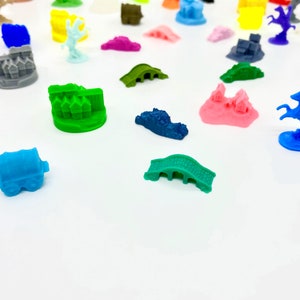 Könnte beinhalten: Eine Sammlung von bunten 3D-gedruckten Miniatur-Spielfiguren, darunter Gebäude, Brücken und ein Ritter zu Pferd. Die Figuren sind aus Kunststoff und für den Einsatz in Brettspielen konzipiert.