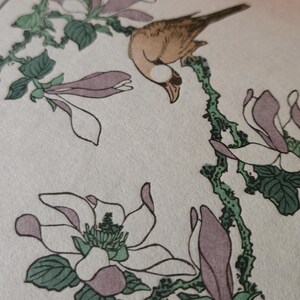 Peut inclure: Un oiseau brun perché sur une branche avec des fleurs de magnolia roses et blanches. Les fleurs sont en fleurs et les feuilles sont vertes. L'arrière-plan est rose pâle.