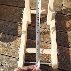 Puede incluir: Un soporte de bicicleta de madera con altura ajustable, medido con una cinta m&eacute;trica que muestra una longitud de 76 cm. El soporte tiene dos varillas met&aacute;licas con tuercas de mariposa para asegurar la bicicleta.