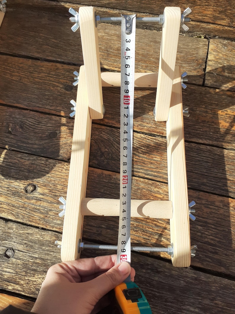 Puede incluir: Un soporte de bicicleta de madera con altura ajustable, medido con una cinta m&eacute;trica que muestra una longitud de 76 cm. El soporte tiene dos varillas met&aacute;licas con tuercas de mariposa para asegurar la bicicleta.