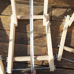Puede incluir: Telar de madera con ancho ajustable, medido con una cinta m&eacute;trica que muestra 76 cm. El telar est&aacute; hecho de madera natural y tiene tornillos de metal para ajustar la tensi&oacute;n.