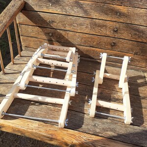 Puede incluir: Un conjunto de telares de madera con varillas met&aacute;licas y botones de tensi&oacute;n ajustables. Los telares est&aacute;n apilados uno encima del otro y est&aacute;n sobre una superficie de madera.