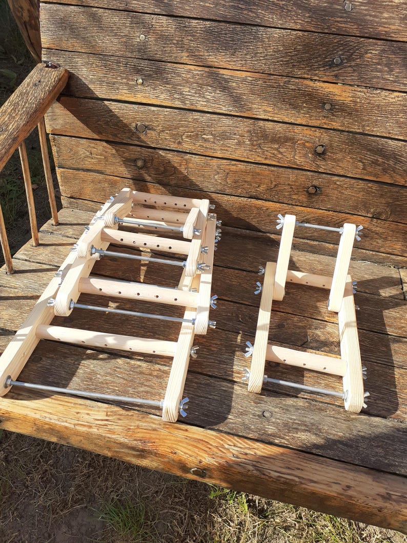 Puede incluir: Un conjunto de telares de madera con varillas met&aacute;licas y botones de tensi&oacute;n ajustables. Los telares est&aacute;n apilados uno encima del otro y est&aacute;n sobre una superficie de madera.