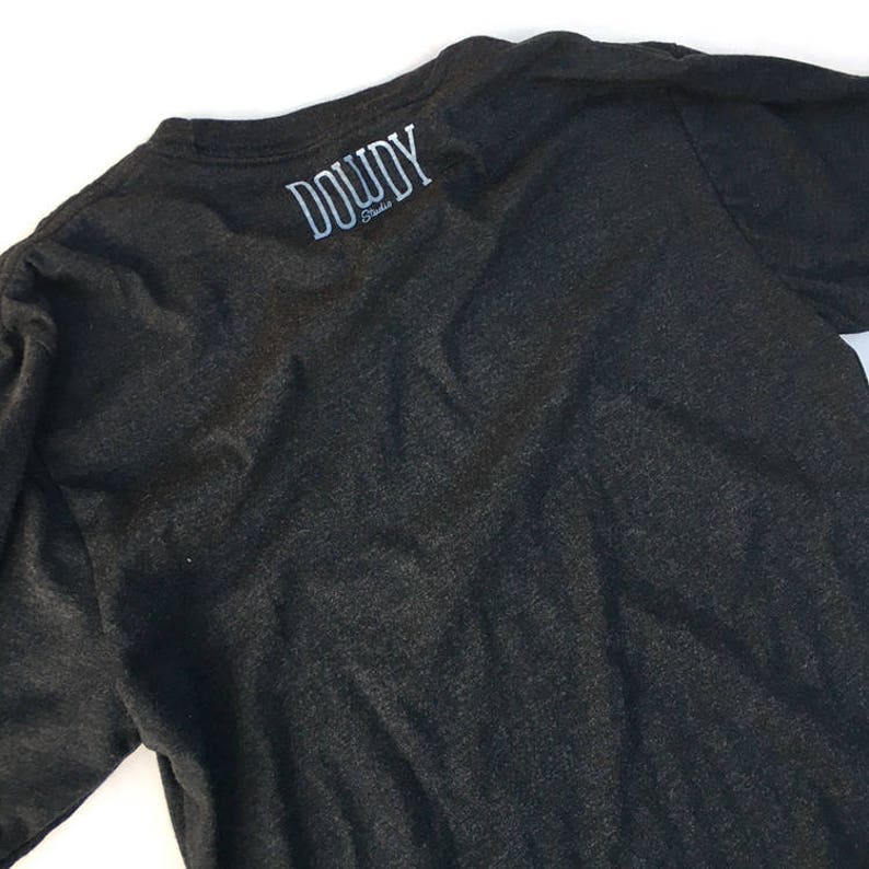 May include: A dark grey t-shirt with the text "DOWDY Studio" printed on the back.