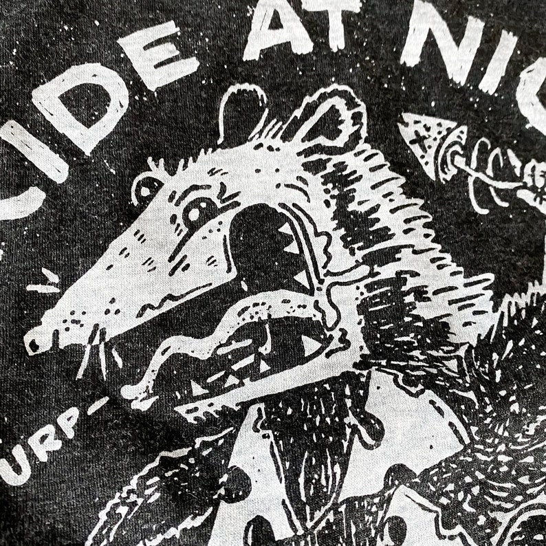 May include: Black and white graphic print of a rat with a large mouth and sharp teeth. The rat is wearing a shirt and has an arrow pointing towards it. The text "SIDE AT NIGHT" is visible above the rat.