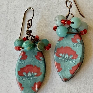 Könnte beinhalten: Türkise Ohrringe mit rotem Blumenmuster und türkisfarbenen und roten Perlen, die unten hängen.