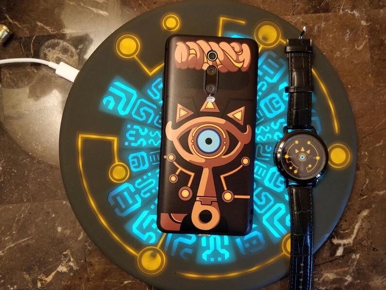 A light up blue and yellow wireless charger with a phone and watch on top of it