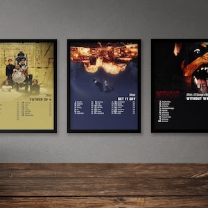 May include: Three framed concert posters with black frames. The posters are for the bands Set It Off, Father of 4, and Without Warning. The posters feature images of the bands and their album titles. The posters are on a grey wall.