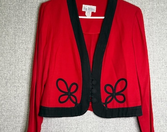 May include: A red jacket with long sleeves and black trim. The jacket has a V-neck design with black buttons and decorative black bow-shaped accents near the hem. The label reads "Peri Petites".