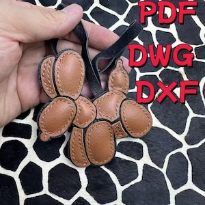 May include: Two brown leather balloon dog keychains with black leather straps. The keychains are stitched with a contrasting thread. The image also includes the text "PDF", "DWG", and "DXF" in red.
