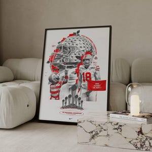 May include: Framed poster with a red and white graphic of a football player and helmet. The poster includes the text "2024 NATIONAL CHAMPIONS" and "OHIO AGAINST THE WORLD". The poster is displayed on a white wall.