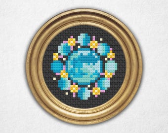 May include: A framed cross-stitch design featuring a blue and green pixelated Earth surrounded by a ring of yellow stars and pink and blue planets.