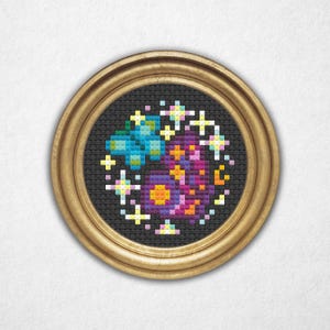 May include: A framed, circular cross-stitch artwork featuring a colorful floral design with a blue butterfly. The artwork is set against a black background and framed in a gold-colored, round frame. The design includes yellow, orange, purple, and white accents.