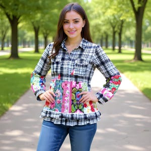 May include: A long-sleeved plaid shirt with a floral patchwork design on the bodice and sleeves. The shirt features a black and white checkered pattern on the upper portion and a ruffled hemline. The model is wearing blue jeans.