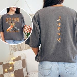May include: A gray t-shirt with a graphic of a dragon and the text "Onyx Storm" and "I Will Save Him". The back of the shirt has a graphic of five dragons.