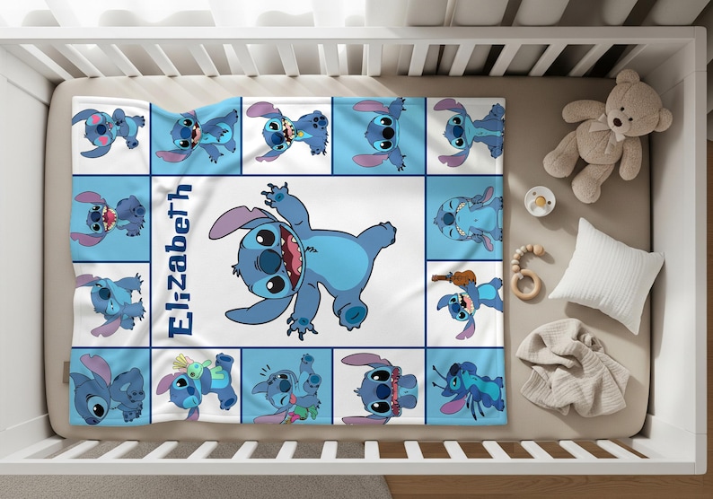 Peut inclure: Une couverture pour b&eacute;b&eacute; avec un motif bleu et blanc repr&eacute;sentant le personnage Stitch de Lilo & Stitch. La couverture pr&eacute;sente un motif quadrill&eacute; avec diverses poses de Stitch et le nom "Elizabeth" en bleu. La couverture est dans un berceau avec un ours en peluche et d'autres articles pour b&eacute;b&eacute;s.
