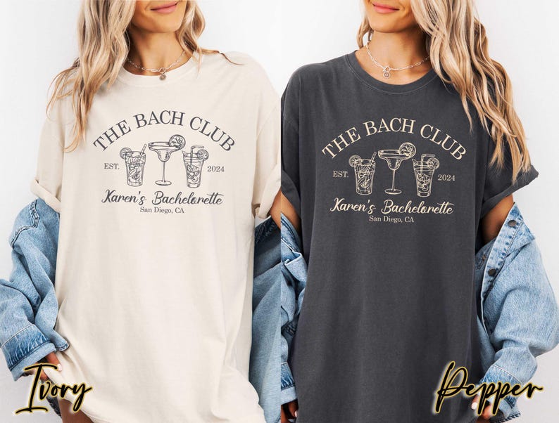 May include: Two women's t-shirts with a black graphic design that says "The Bach Club" with a date and the text "Karen's Bachelorette" with a city and state. The t-shirts are in ivory and pepper colors.