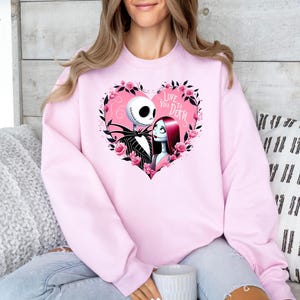 Może przedstawiać: R&oacute;żowa bluza z nadrukiem Jacka Skellingtona i Sally z filmu Koszmar przed świętami. Nadruk przedstawia serce z tekstem "Love You To Death".
