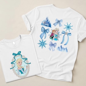 May include: Two white t-shirts featuring designs from the animated film, Frozen. One shirt displays Elsa in an oval frame with a blue bow. The other shirt has various blue bows, snowflakes, and a castle design.