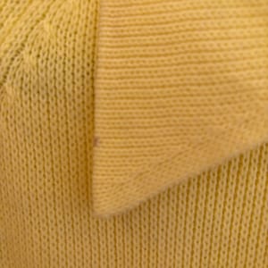 May include: Close-up of a pale yellow knit fabric, possibly a sweater or top. The texture is visible with vertical ribbing and a V-neck collar. The fabric appears soft and comfortable, suitable for casual wear.