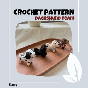 Könnte beinhalten: Häkelmuster für ein Dackelteam. Das Muster ist einfach zu befolgen und enthält Anleitungen zum Herstellen von vier verschiedenen Dackeldesigns: einem schwarz-weiß gefleckten Dackel, einem schwarzen Dackel, einem weißen Dackel mit blauen Akzenten und einem braunen Dackel mit einem rot-weißen Pullover. Die Dackel sitzen alle auf einem Holztablett.