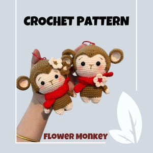 Könnte beinhalten: Häkelanleitung für einen Blumen-Affen. Zwei braune gehäkelte Affen mit roten Schals und weißen Blumenakzenten. Das Muster heißt "Flower Monkey".