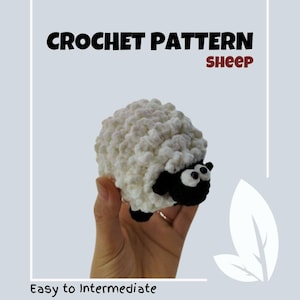 May include: Crochet pattern for a white sheep with black face and eyes. The sheep is being held in a hand. The text "CROCHET PATTERN sheep" is at the top of the image. The text "Easy to Intermediate" is at the bottom of the image.