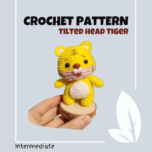 May include: Crochet pattern for a tilted head tiger amigurumi. The tiger is yellow with white stripes and a pink nose. The pattern is for an intermediate skill level.