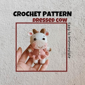 May include: Crochet pattern for a dressed cow amigurumi. The cow is white with brown spots and wears a pink dress. The pattern is for easy to intermediate crocheters.