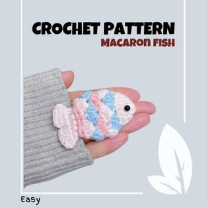 May include: Crochet pattern for a macaron fish. The fish is pink, blue and white and has a black eye. The pattern is easy to follow.