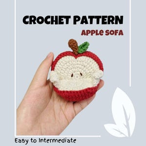 Puede incluir: Patrón de crochet para un sofá con forma de manzana. El sofá es rojo con un interior blanco y una hoja verde en la parte superior. El patrón se describe como fácil a intermedio.