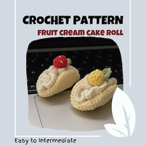 Puede incluir: Patrón de crochet para un rollo de pastel de crema de fruta. El patrón se describe como fácil a intermedio. La imagen muestra dos rollos de pastel de crochet, uno con una fresa roja y el otro con un limón amarillo.
