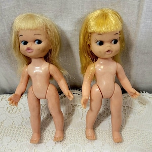 Par de muñecas vintage pequeñas de 5-1/2&quot; fabricadas en Hong Kong. Ojos de reojo, cuerpos de plástico duro con cabezas de vinilo.