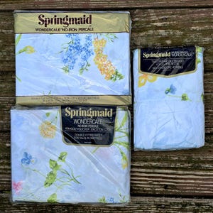 May include: Three packages of Springmaid Wondercale no-iron percale bedding. The packages contain a double flat sheet, a double fitted sheet, and two standard pillowcases. The sheets have a floral pattern with blue, yellow, and pink flowers.