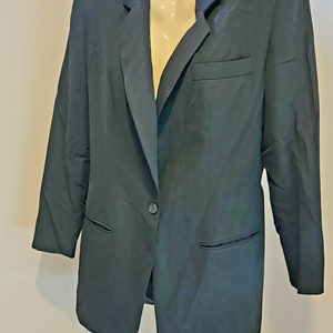 May include: A dark navy blazer with a single-button closure, two front pockets, and a notched lapel. The jacket is displayed on a mannequin. The blazer is a classic style, suitable for various occasions.