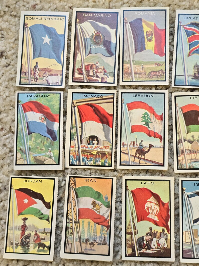 Op de afbeelding: Een verzameling van 12 vintage verzamelkaarten met vlaggen uit verschillende landen. Elke kaart heeft een kleurrijke illustratie van de vlag, samen met de naam van het land gedrukt in zwarte tekst.