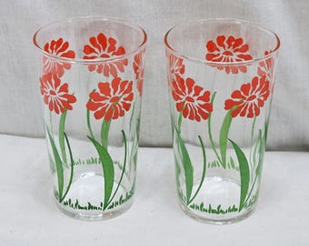 Vaso Federal Glass Swanky Swigs, flores vermelhas com múltiplas pétalas e folhas verdes em forma de espada.