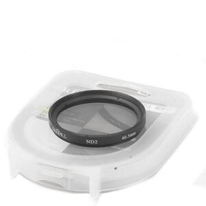 Op de afbeelding: Een zwarte ND2 cameralensfilter met een diameter van 40,5 mm ligt op een doorzichtige plastic doos. De filter heeft witte tekst met "GREEN.L" en "40,5 mm". De doos is licht transparant.