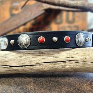 Könnte beinhalten: Schwarzes Leder-Halsband für Hunde mit silberfarbenen Nieten, roten Edelstein-Akzenten und silbernen Büffelnickel-Details. Das Halsband hat ein Metallschild.