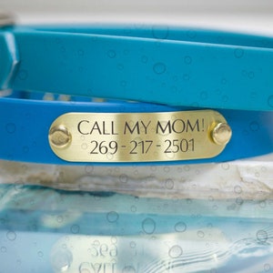 Pode incluir: Duas coleiras de c&atilde;o azuis com etiquetas de nome de metal dourado. A coleira superior &eacute; azul turquesa e a coleira inferior &eacute; azul mais escuro. A etiqueta de nome na coleira inferior diz "CALL MY MOM! 269-217-2501".