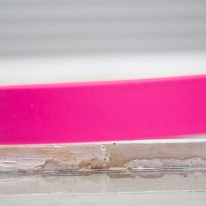 May include: A bright pink silicone watch band with a small hole on the side.