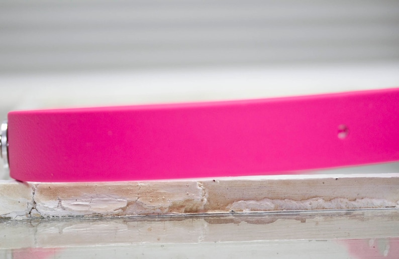 May include: A bright pink silicone watch band with a small hole on the side.
