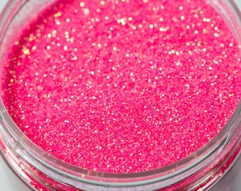 May include: A close-up of a jar filled with pink glitter. The glitter is very fine and has a slight iridescent sheen.