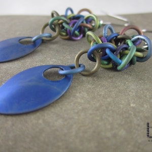 May include: A pair of blue teardrop-shaped earrings with a multi-colored chain link design. The chain links are in shades of blue, green, purple, and gold.