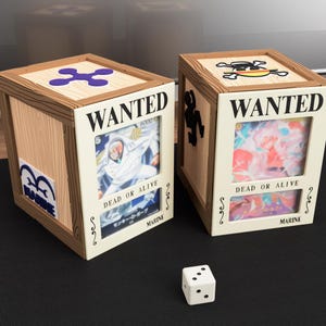 May include: Two wooden crates with "WANTED" posters and character art, one with a purple symbol and the other with a skull and crossbones. The crates have "DEAD OR ALIVE" text and a white die is in front.