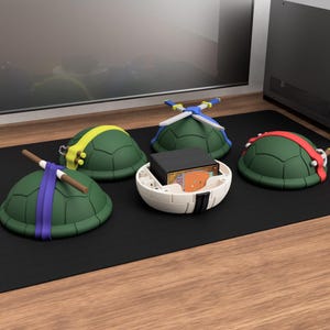 Puede incluir: Contenedores de almacenamiento verdes con forma de caparaz&oacute;n de tortuga con cintas para la cabeza y accesorios de colores. Un contenedor est&aacute; abierto, revelando una caja negra y cartas. Los contenedores est&aacute;n sobre una superficie negra.