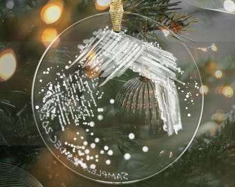 Peut inclure: Une boule de Noël en verre transparent avec un motif abstrait blanc et le texte "SAMPLE 23DEC SOS" sur le devant.