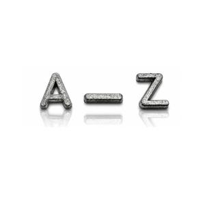 May include: Silver-colored letters A, a dash, and Z, arranged horizontally. The letters and dash have a textured, speckled appearance, possibly metallic. The objects are set against a white background with a subtle reflection.