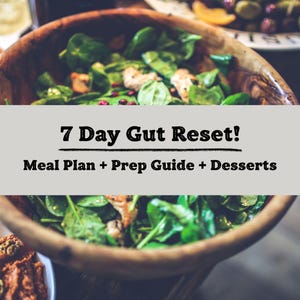May include: A wooden bowl filled with a fresh green salad, with the text "7 Day Gut Reset! Meal Plan + Prep Guide + Desserts" overlaid on the image. Other dishes with food are visible in the background.